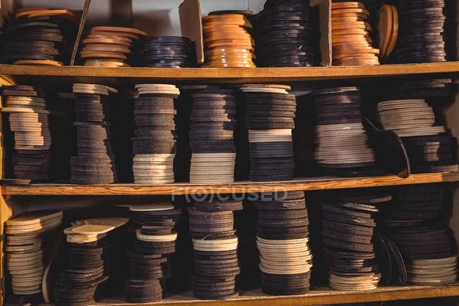 Montones de plantillas de zapatos de cuero en estantes en taller de calzado - foto de stock