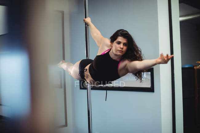 Attractive Pole dancer practicing pole dance in fitness studio — Stock Photo