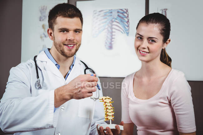 Portrait of physiotherapist explaining spine to female patient in clinic — Stock Photo