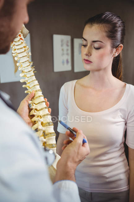 Physiothérapeute expliquant la colonne vertébrale au patient en clinique — Photo de stock