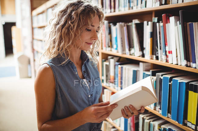 Schöne Frau liest Buch in Bibliothek — Stockfoto