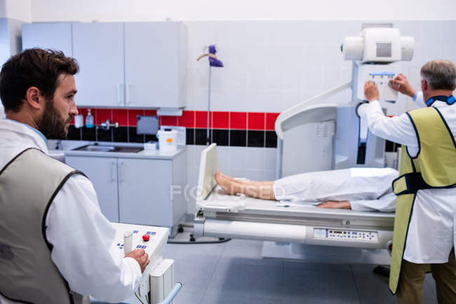 Médicos usando máquina de rayos X para examinar al paciente en el hospital - foto de stock