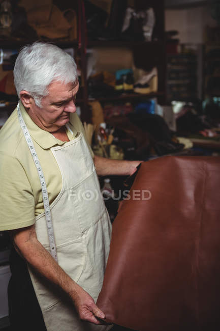 Schuhmacher begutachtet in Werkstatt ein Stück Leder — Stockfoto