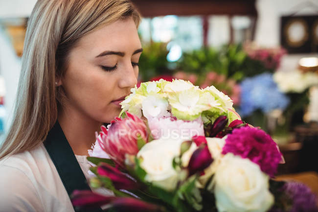 Female florist smelling flower bouquet at her flower shop — Stock Photo
