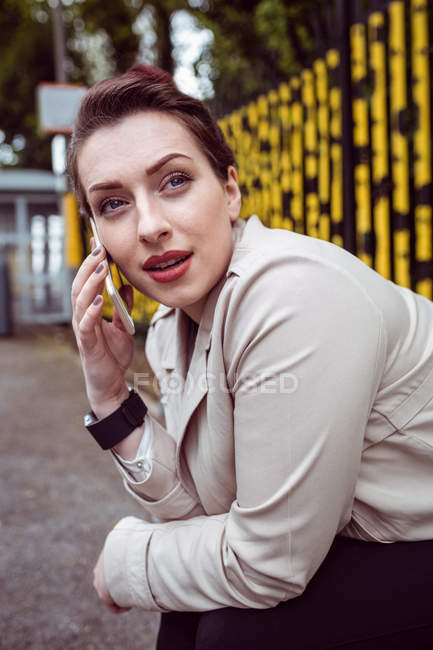 Young woman talking on phone at railroad station platform — Stock Photo