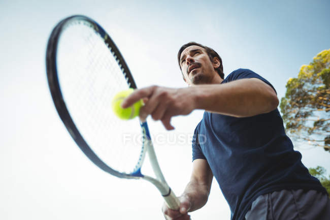 Низький кут зору людини з тенісною ракеткою, готовою служити в спортивному корт — стокове фото