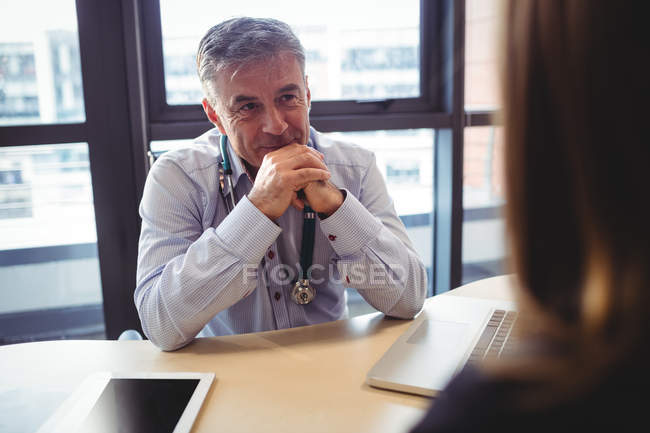 Medico di sesso maschile alla scrivania parlando con il paziente in ospedale — Foto stock