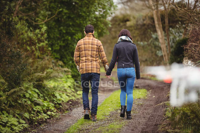Visão traseira do casal andando na pista de sujeira no campo — Fotografia de Stock