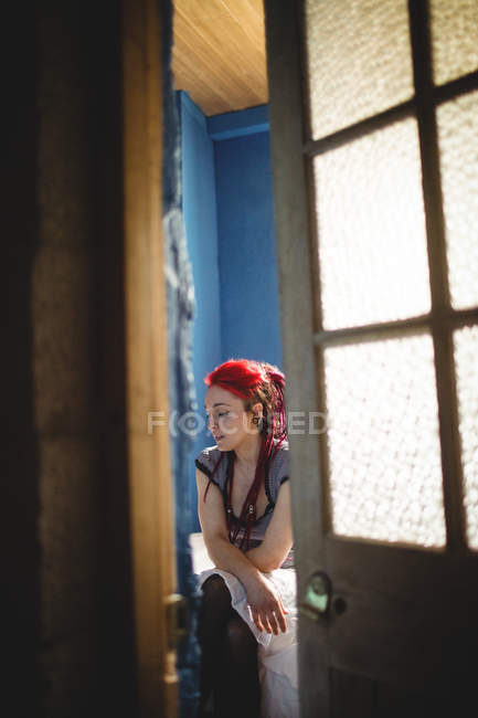 Молода жінка з фарбованим волоссям сидить на ліжку вдома — стокове фото