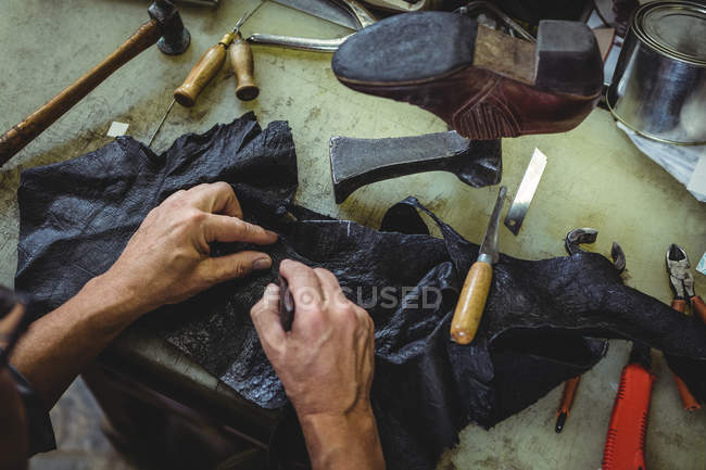 Hands of shoemaker cutting a piece of material in workshop — Stock Photo