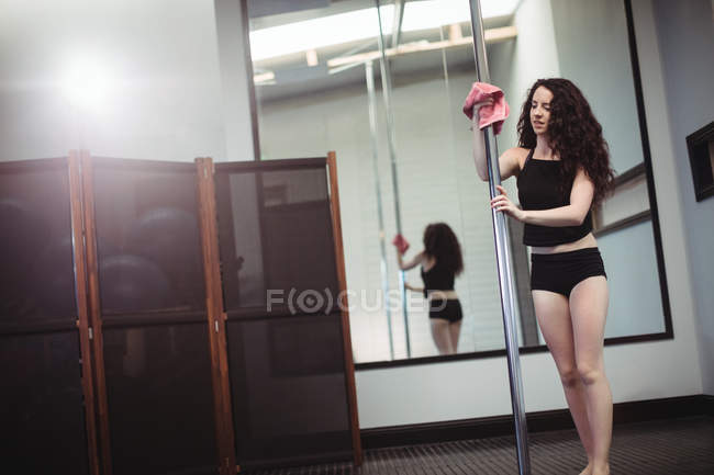 Pole dancer cleaning pole in fitness studio — Stock Photo