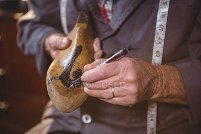 Close-up of shoemaker marking on shoe last with pen in workshop — Stock Photo