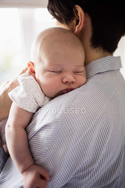 Baby sleeping on mother shoulder at home — Stock Photo