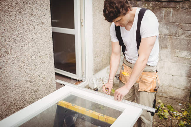 Charpentier mesurant le cadre de porte avec crayon — Photo de stock