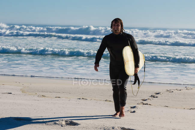 Surfista che cammina sulla spiaggia in una giornata di sole — Foto stock