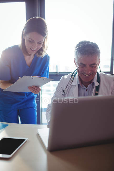 Médico discutindo com enfermeira sobre laptop no hospital — Fotografia de Stock