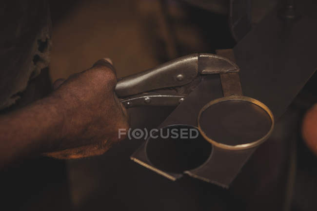 Close-up of blacksmith holding metal piece with tongs at work shop — Stock Photo