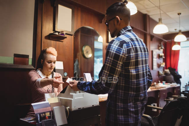 Человек делает платеж с помощью своей кредитной карты в парикмахерской — стоковое фото