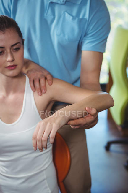 Fisioterapeuta estirando brazo de paciente femenina en clínica - foto de stock
