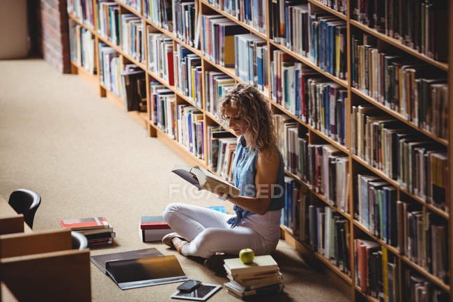 Mulher sentado e lendo livro na biblioteca — Fotografia de Stock