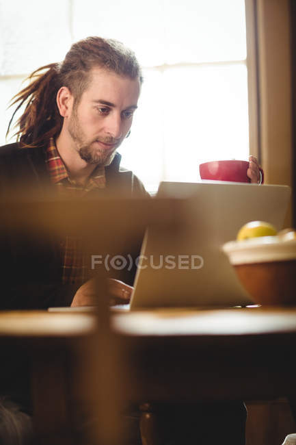 Hipster hombre usando el ordenador portátil en casa - foto de stock
