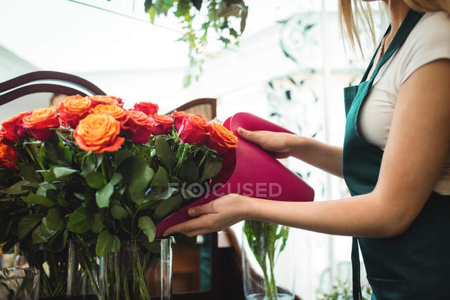 Seção média de florista feminina derramando água em vaso de flores em sua loja de flores — Fotografia de Stock