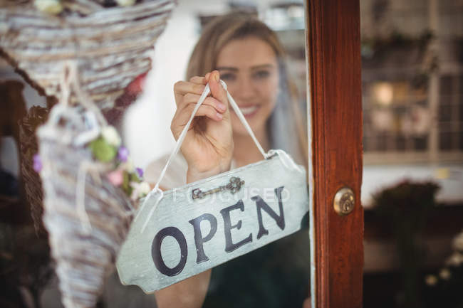 Female florist holding open signboard in the flower shop — Stock Photo