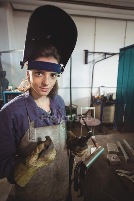 Female welder holding welding torch in workshop — Stock Photo