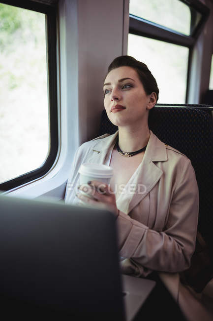 Thoughtful beautiful woman sitting by window in train — Stock Photo