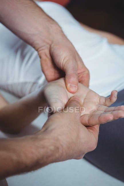 Imagen recortada de fisioterapeuta masajeando mano de paciente femenina en clínica - foto de stock