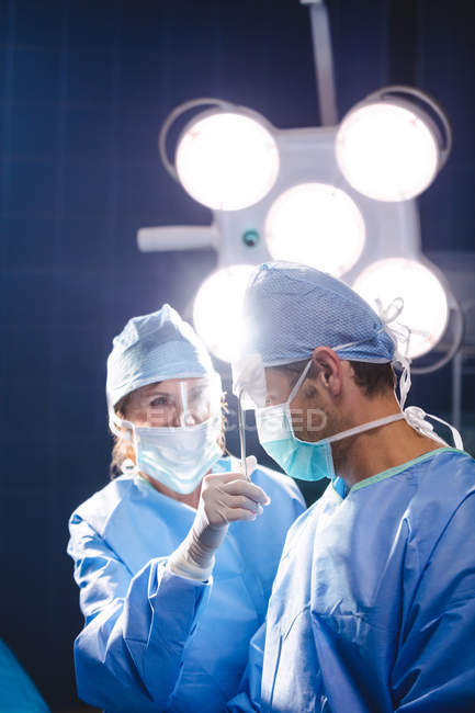 Cirujanos sonrientes interactuando en la sala de operaciones del hospital - foto de stock