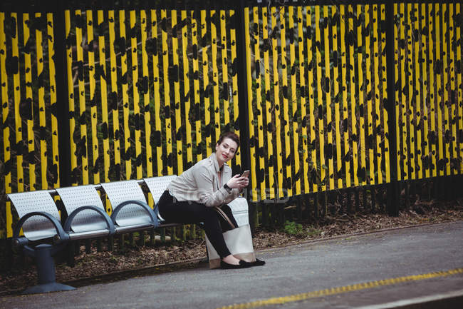 Ritratto di giovane donna seduta sulla panchina della stazione ferroviaria — Foto stock