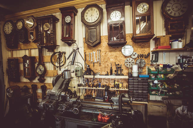 Antiguo taller de relojería con herramientas de reparación de relojes, equipos y relojes en la pared - foto de stock