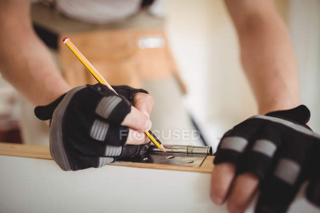 Cropped image of Carpenter measuring wooden door with pencil at home — Stock Photo