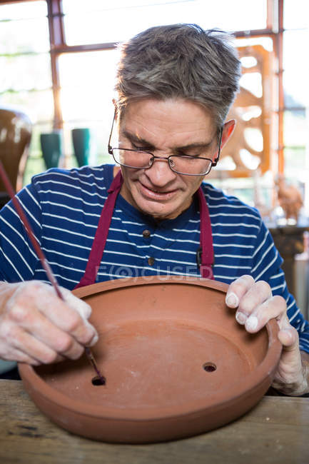 Gros plan de la peinture de potier masculin sur pot en atelier — Photo de stock