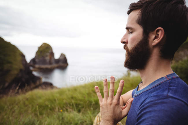 Close-up of man performing yoga on cliff — Stock Photo