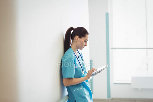 Enfermera usando tableta digital en la pared del hospital - foto de stock
