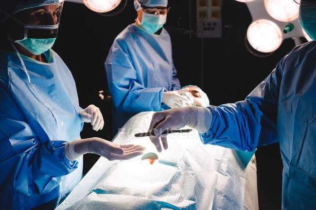 Chirurg übergibt OP-Messer an Kollegin im Operationssaal des Krankenhauses — Stockfoto