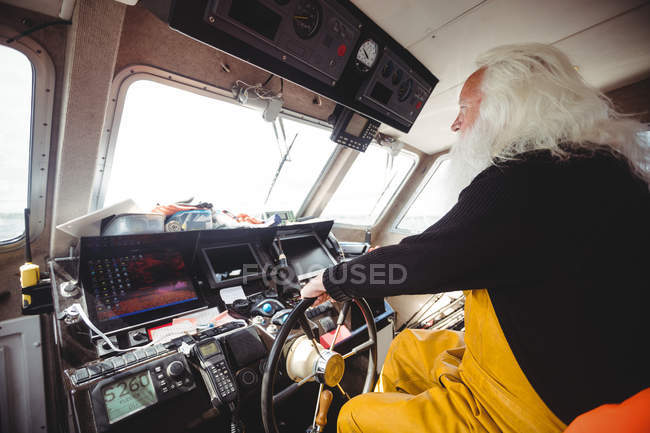 Side view of Fisherman driving fishing boat on sunny day — Stock Photo