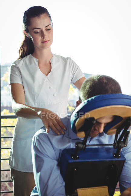Fisioterapista femminile che dà massaggio alla schiena al paziente maschile in clinica — Foto stock