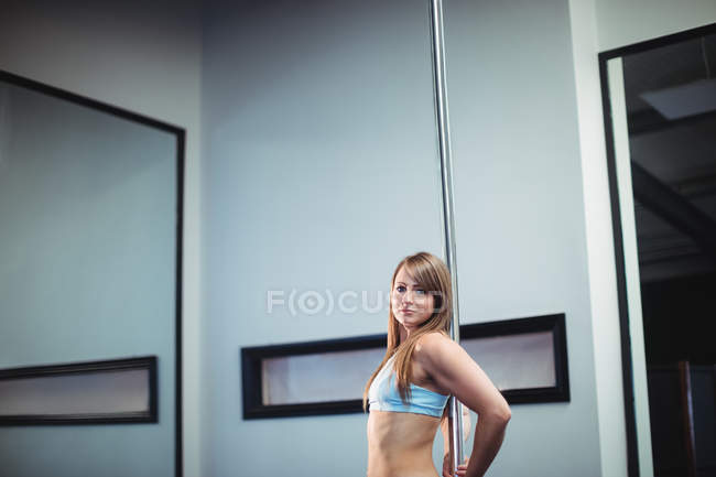 Portrait of pole dancer leaning against pole in fitness studio — Stock Photo