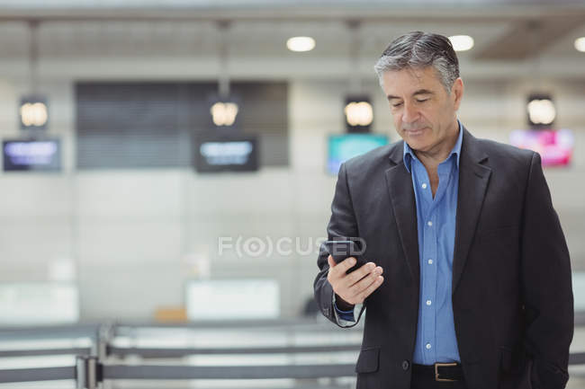 Homme d'affaires utilisant le téléphone portable dans le terminal de l'aéroport — Photo de stock