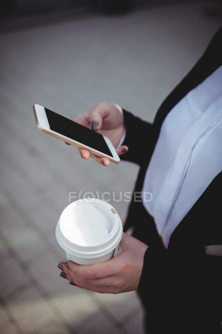 Midsection de femme d'affaires utilisant le téléphone mobile dans la rue — Photo de stock