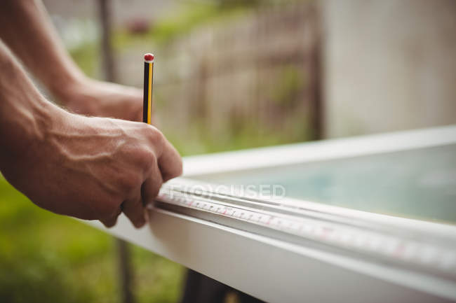 Обрезанное изображение плотника, измеряющего дверную раму — стоковое фото