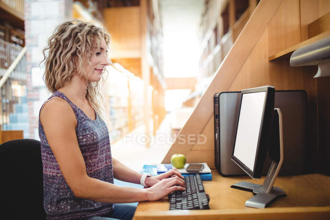 Bella donna che lavora al computer in biblioteca — Foto stock