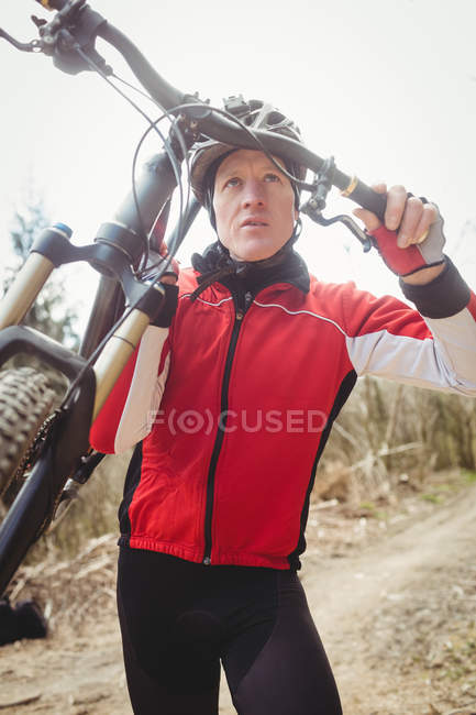 Frontansicht eines Mountainbikers, der Fahrrad gegen den Himmel trägt — Stockfoto