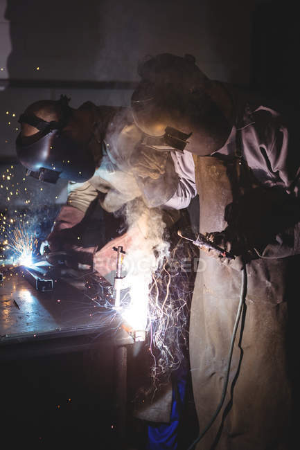 Welders welding metal in workshop — Stock Photo
