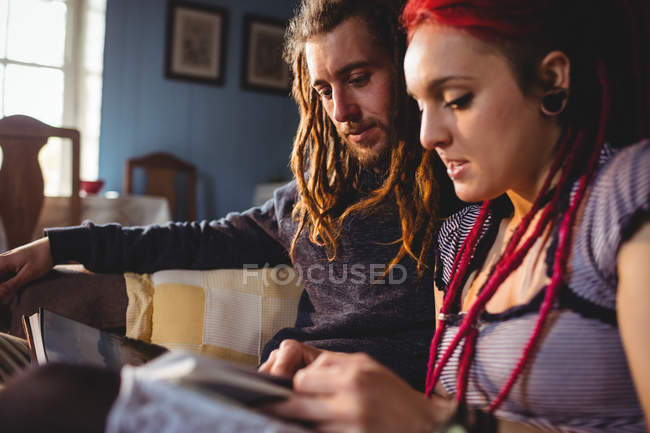 Jeune couple regardant album photo assis à la maison — Photo de stock