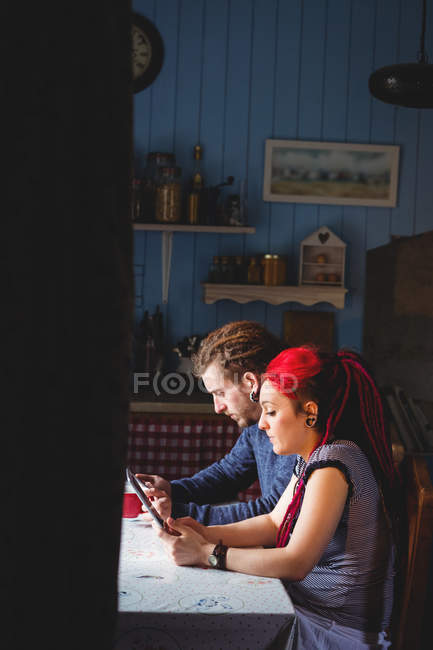 Умная пара с помощью цифрового планшета, сидя дома — стоковое фото