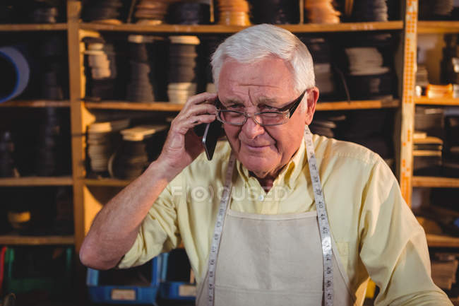 Schuster telefoniert in Werkstatt mit Handy — Stockfoto
